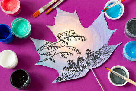 Hand-painted dry autumn maple leaves. Autumn countryside landscape on maple leaf, brushes and paints on purple background. Creative autumn art projectの写真素材