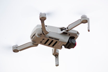 White drone quadrocopter flies against background of white wall of building and makes filming. Technology of photography of drones. Remote control. Shallow depth of fieldの写真素材