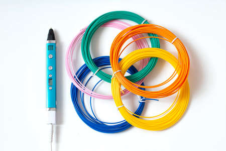 3D pen and multi-colored plastic for drawing with it on white background. 3D pen - modern device for creating flat and three-dimensional objects with hot plasticの写真素材