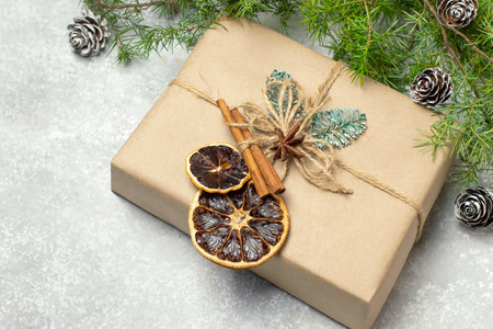 Christmas gift box decorated with dried orange slices, cinnamon and star anise. Eco-friendly reusable paper gift box with natural edible decorations. Twigs of Christmas tree with conesの写真素材