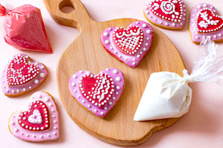 Decorating handmade gingerbread with icing. Glaze in pastry bags. Heart shaped gingerbread for Valentine's Dayの写真素材
