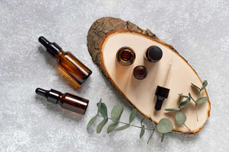 Glass cosmetic bottles with dropper and eucalyptus branches. Natural essential oils and skin care products. Concept of natural cosmeticsの写真素材