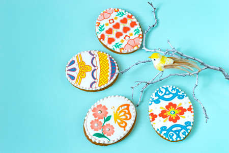 Colorful painted Easter egg-shaped gingerbread and decorative sprig with bird. Gingerbread are covered with sugar glaze and decorated with beautiful color patternsの写真素材