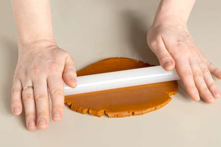 Female hands roll out dark honey gingerbread dough with fragrant spices. close-upの写真素材