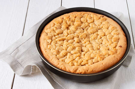 Homemade shortbread pie with almond chocolate filling in baking dish on white wooden table