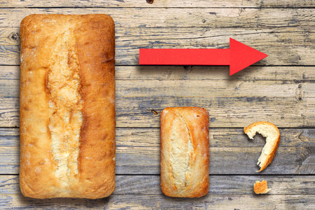 Large and small loaf of wheat bread with red arrow and question mark made of bread crusts. Concept of wheat shortage, food crisis and famine. Rising wheat pricesの写真素材