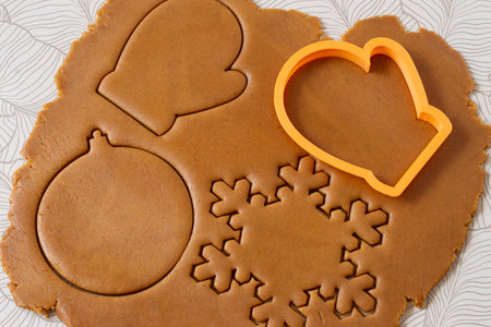 Cutting out Christmas gingerbread from dark honey dough with spices. Dough and various cookie cutters on tableの写真素材