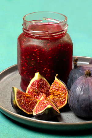 Delicious fig jam in glass jar and ripe fresh figs on gray plate close-up. fruit canningの写真素材