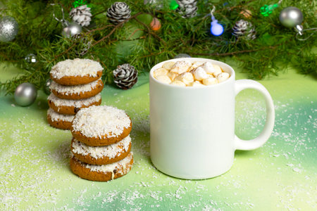 Mockup of white mug with hot chocolate and marshmallows and coconut cookies on table with Christmas decor. Mug, coconut cookies, Christmas tree and luminous garlandの写真素材