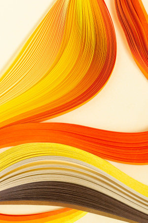 Abstract pattern of quilling stripes of yellow, orange and brown shades on yellow paper backgroundの写真素材