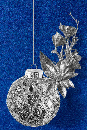 Beautiful silver Christmas ball and sprig decorated with glitter, sequins and rhinestones on blue glitter background for Christmas decorの写真素材