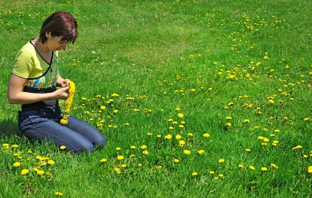 girl resting on the green meadow with dandelion flowers の写真素材