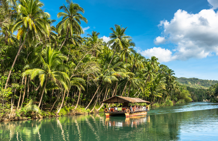 traditional raft boat with tourists on a jungle green river Loboc at Bohol island of Philippinesのeditorial素材
