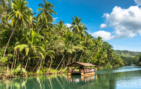 traditional raft boat with tourists on a jungle green river Loboc at Bohol island of Philippinesの写真素材