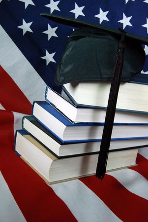 Stack of school books with grad hat on flag.の写真素材