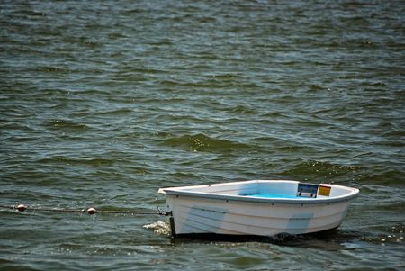 Little dinghy being towed on the water.
