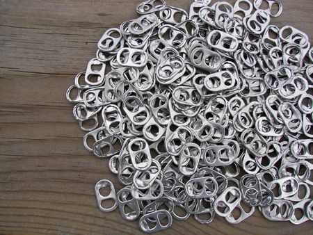 Soda pop tabs on a worn table.