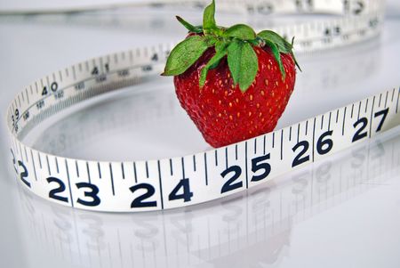 Strawberry with a measuring tape on a shiny surface.の写真素材
