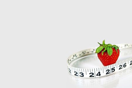 Strawberry with tape measure on a shiny white surface.の写真素材