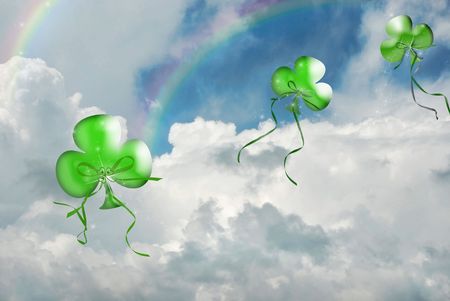 Floating shamrock balloons and rainbows in sky.の写真素材