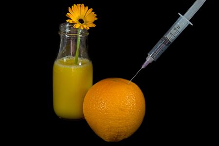 Syringe in an orange with a daisy in orange juice.の写真素材