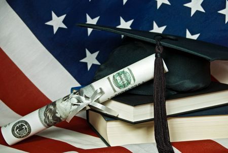 Graduation cap with cash diploma on an American flag.の写真素材