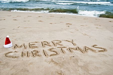 Santa hat and holiday greeting in sand.の写真素材
