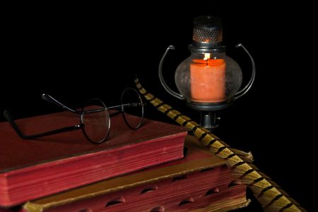 Glowing candle with glasses and feather on Bible.の写真素材
