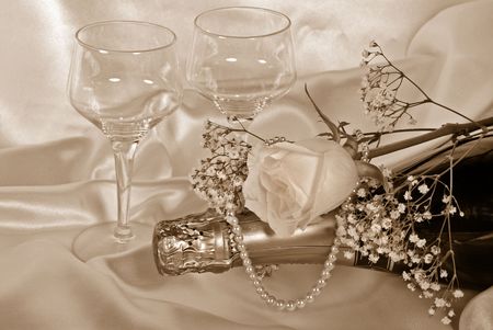 Rose and pearls on wine bottle with stemware in sepia.の写真素材