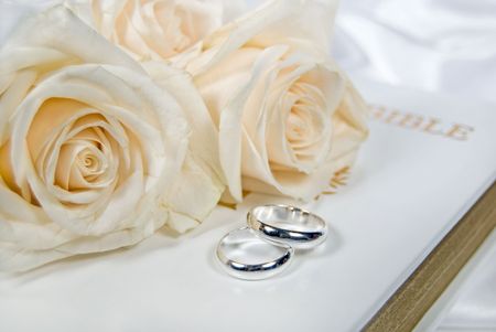 Roses and silver wedding rings on Bible.の写真素材