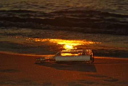 Message in bottle on a sunset beach.の写真素材