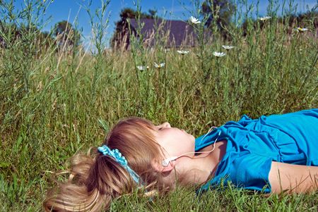 Little girl listening to music in a daisy field.の写真素材