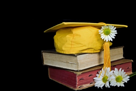 Gold graduation hat on books with daisies.の写真素材
