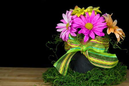 Colorful daisies in pot with bow.