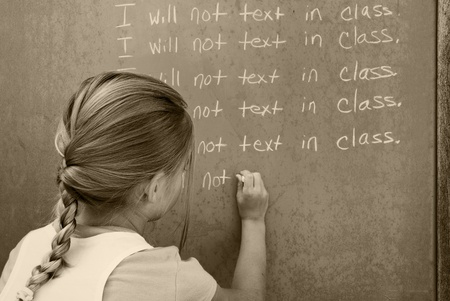 student writing lines on chalkboardの写真素材