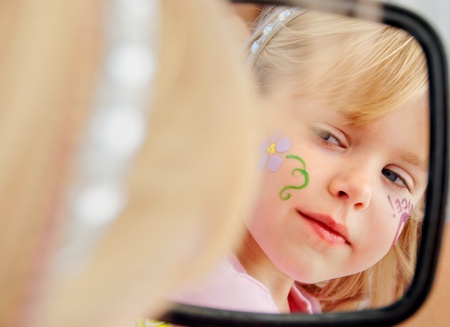 girl looking in mirror with face paint