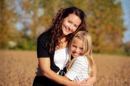 Mother and daughter huggin in a country field