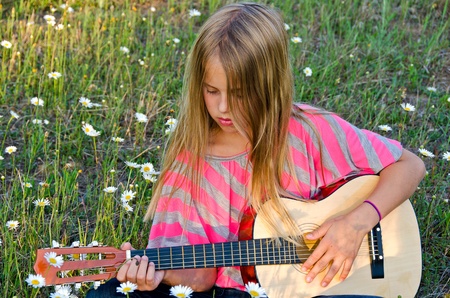 girl with guitar in wild daisy meadowの写真素材