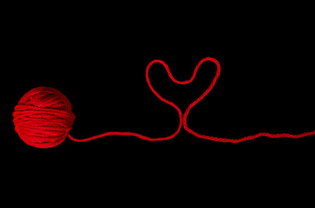 red ball of yarn with heart on blackの写真素材