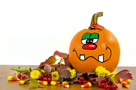 funny fall pumpkin in leaves and candy cornの写真素材