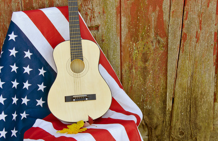 guitar and autumn leaves on American flag by old barnの写真素材