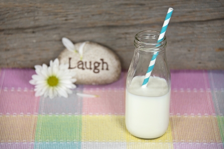 white milk and straw in retro milk bottle with daisyの写真素材