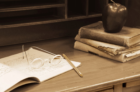old-fashioned eye glasses on teacher's desk with booksの写真素材