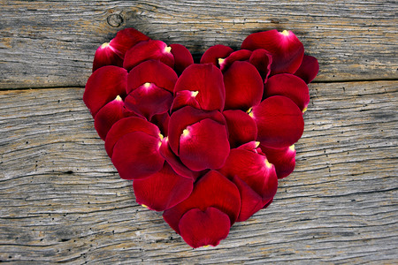 red rose petals in a heart shape on barn woodの写真素材