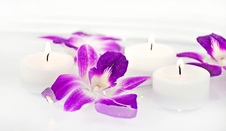 orchid blooms and white lit candles floating in waterの写真素材