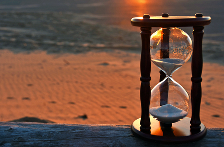 sand timer on beach log with sunset glowの写真素材