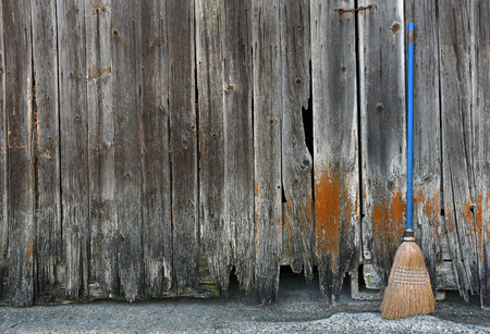 old broom with blue handle leaning on barn wood sidingの写真素材