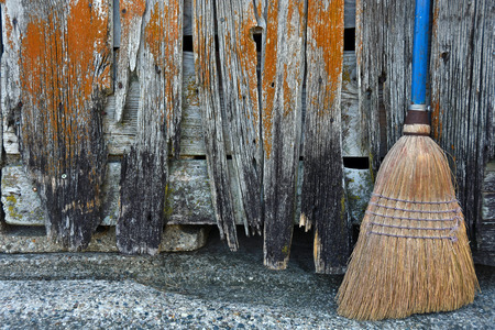 old broom with blue handle by dilapidated barnの写真素材