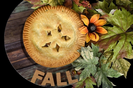 apple pie on wood plate with autumn leaves and flowerの写真素材