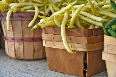 raw yellow beans in wooden produce box and bushel basket at the market